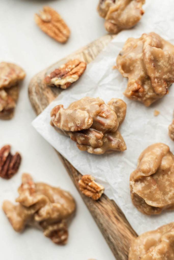 An overhead view of southern pralines on a wood serving board on a countertop. 