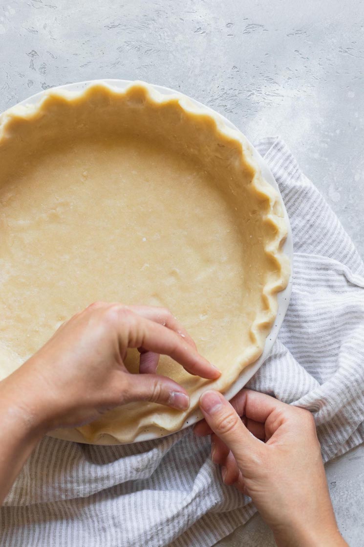 The edges of a pie crust being decorated.