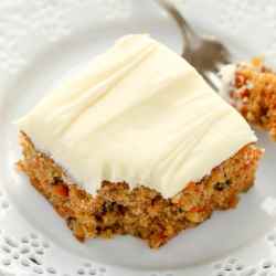A slice of pineapple carrot cake on a white plate with a fork.