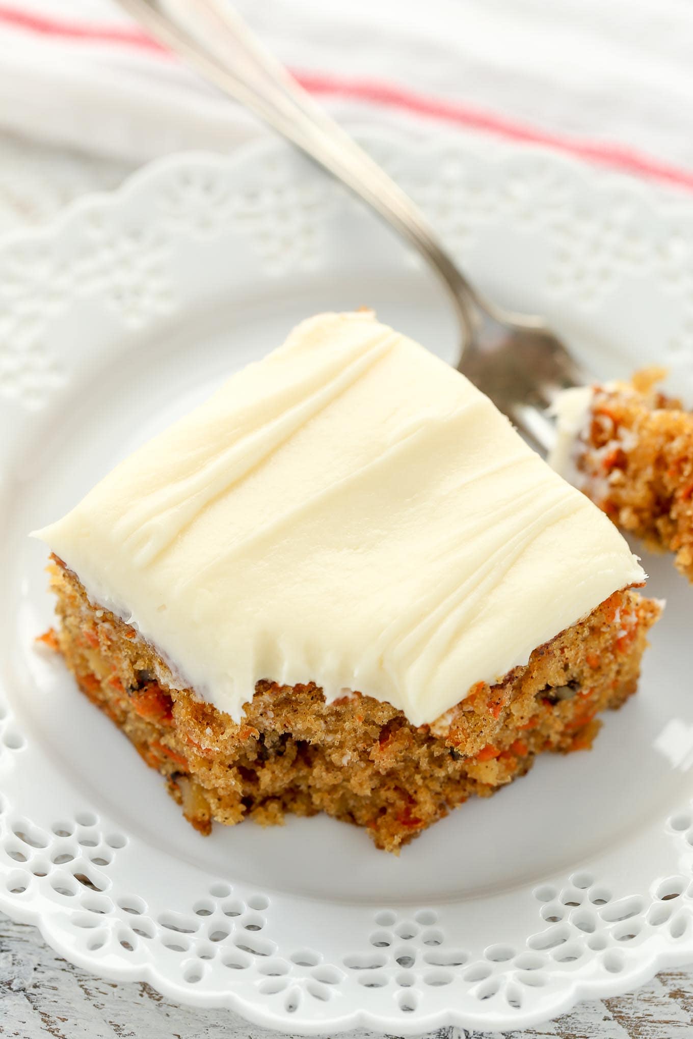 A slice of pineapple carrot cake on a white plate with a fork. 