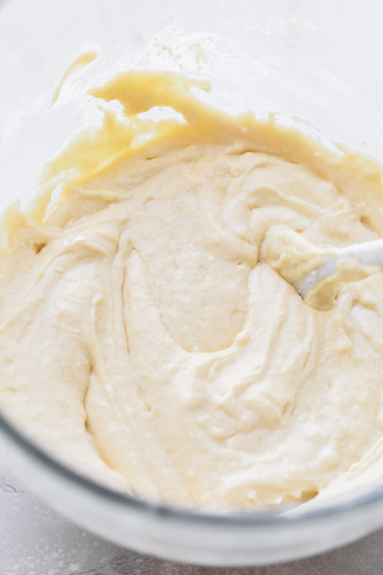 A glass mixing bowl holding cake batter that has been mixed up.