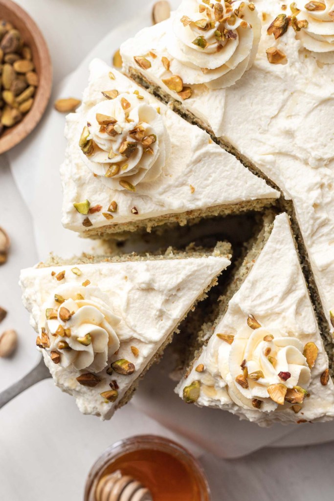 An overhead view of a sliced pistachio layer cake. 