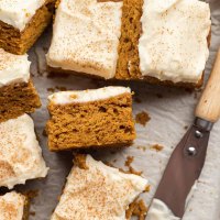 Several slices of pumpkin bars on a piece of parchment paper. One slice is turned on its side to show the texture.