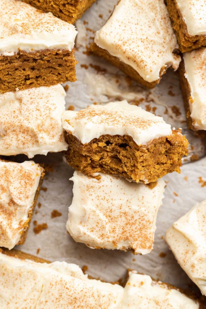 Sliced pumpkin bars with cream cheese frosting, with some turned on their sides. 