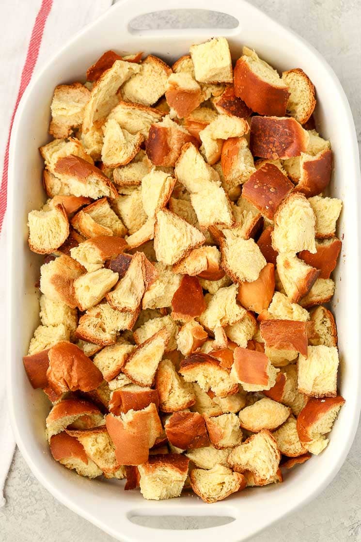 Overhead view of cubed challah bread in a white baking dish. 