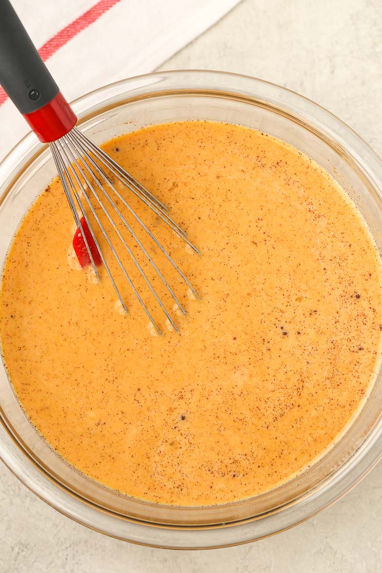 Wet ingredients for homemade bread pudding in a glass bowl with a whisk. 