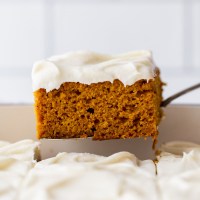 A single piece of cake being removed from the baking dish showing the cake and frosting layers.