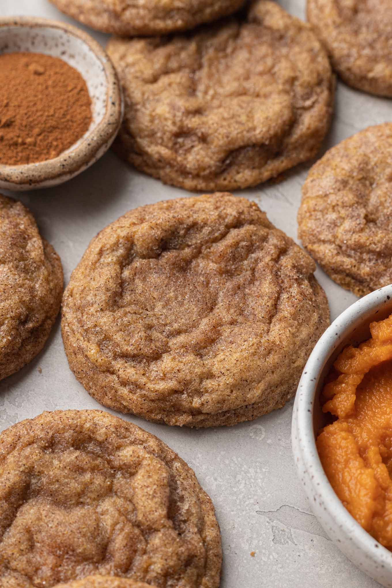 A close-up view of cream cheese-filled pumpkin cookies, next to a dish of pumpkin puree.  