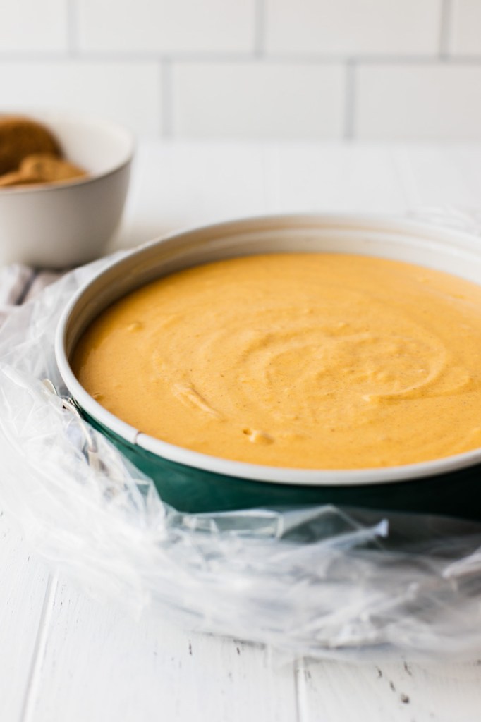 A spring form pan filled with cheesecake filling wrapped in an oven bag to bake in a water bath.