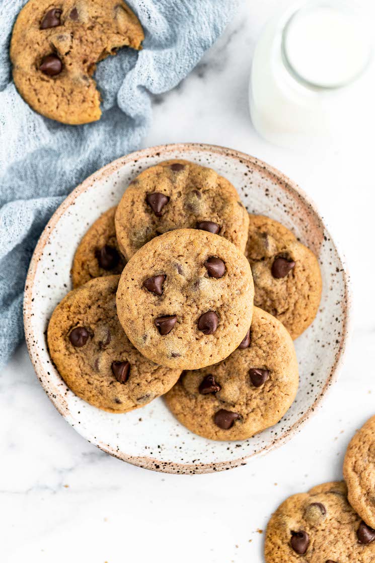 Pumpkin chocolate chip cookies on a speckled plate with milk and more cookies around them.