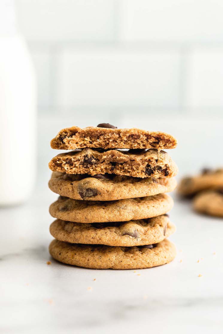 A stack of pumpkin chocolate chip cookies with milk in the background.