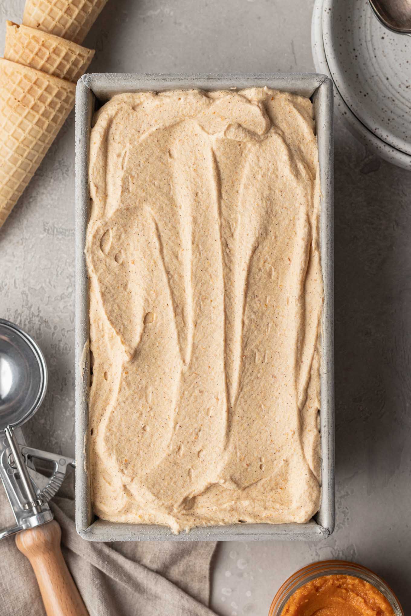 An overhead view of a loaf pan filled with pumpkin ice cream. 