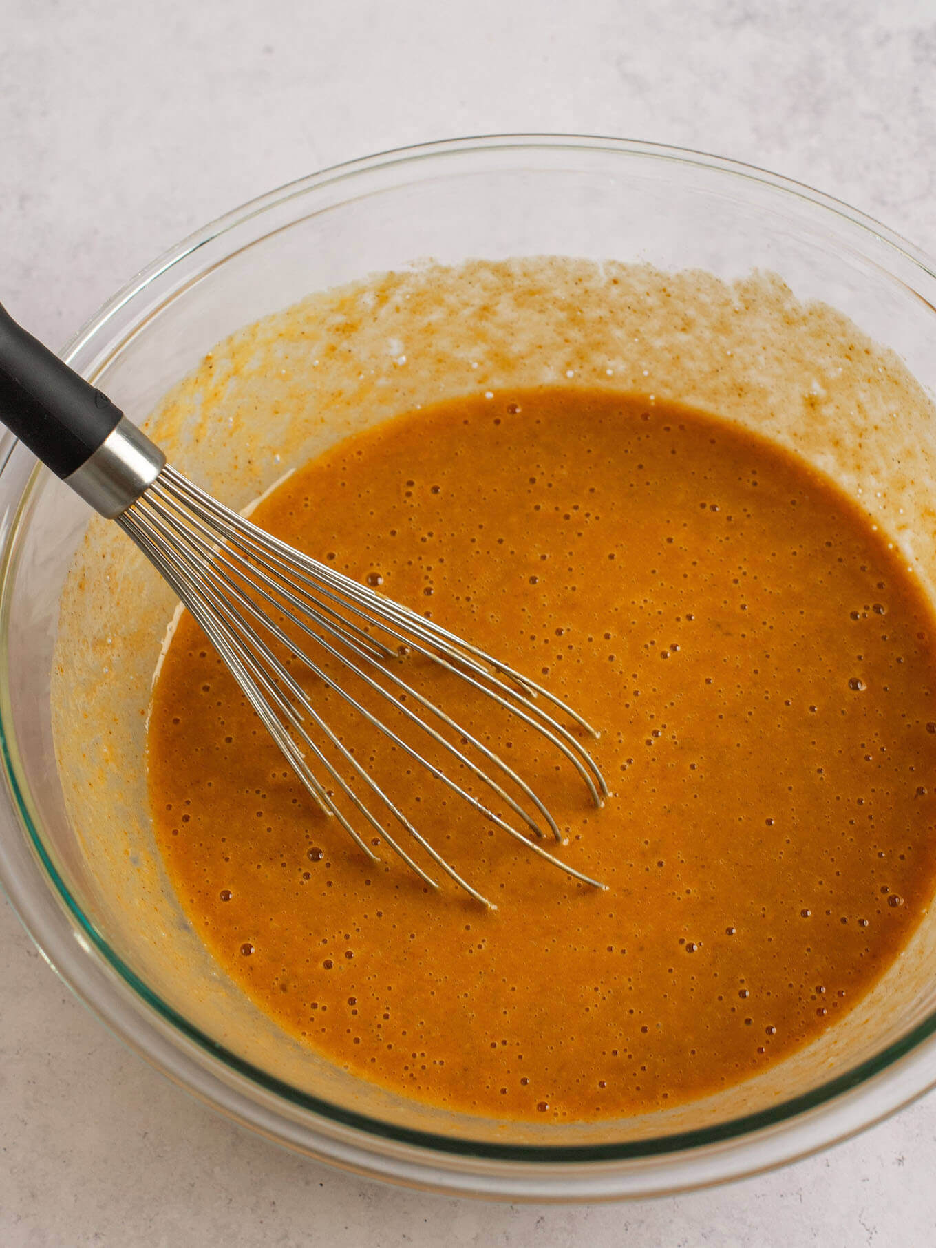 Pumpkin pie filling whisked together in a glass mixing bowl.