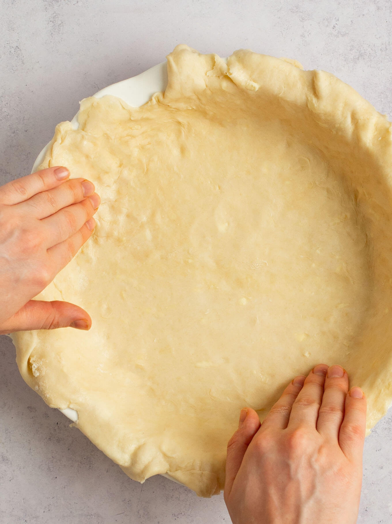 Pie dough being fitted into a pie dish.