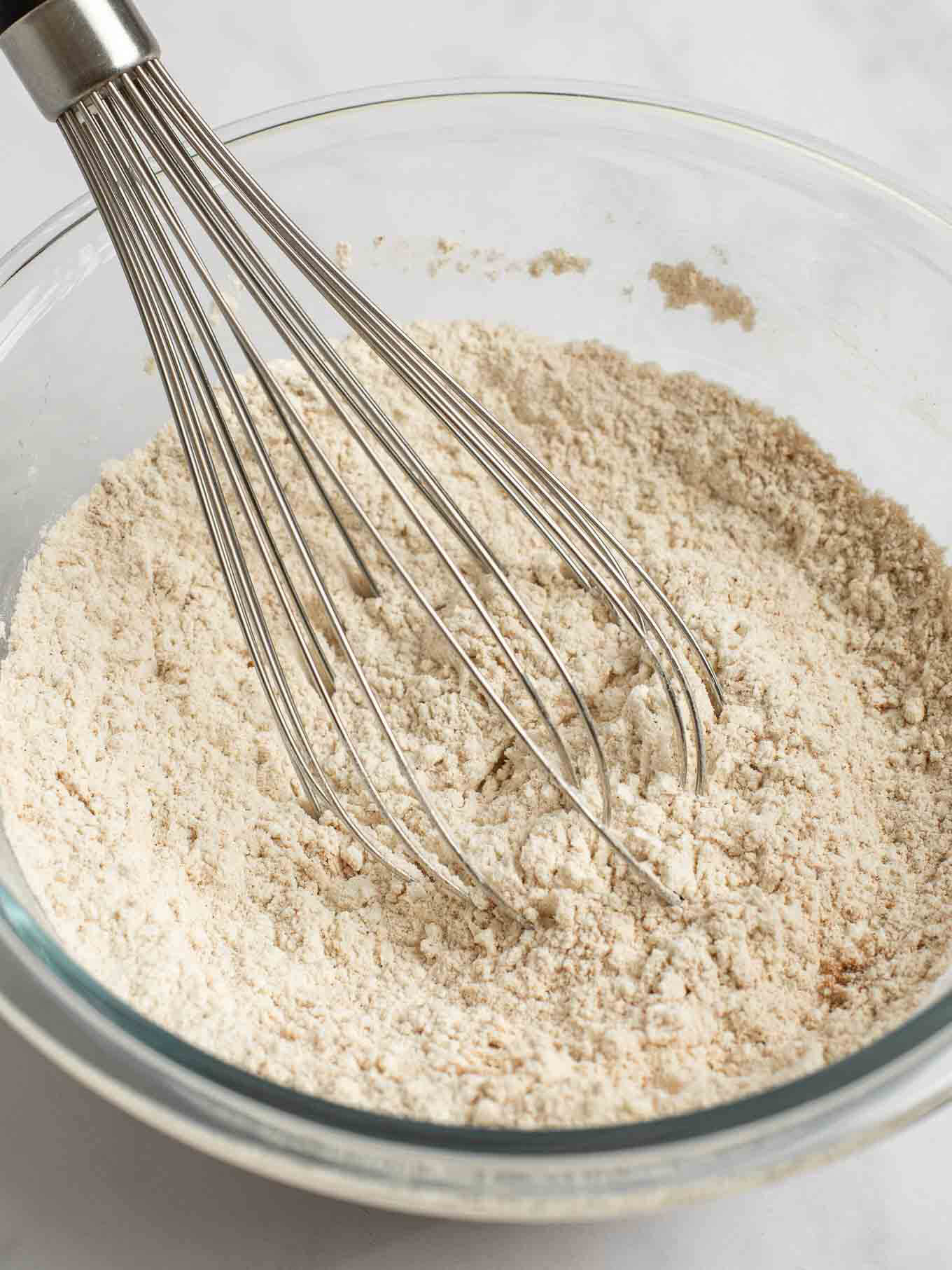 Flour, spices, baking soda, cream of tartar, and salt whisked together in a glass mixing bowl.