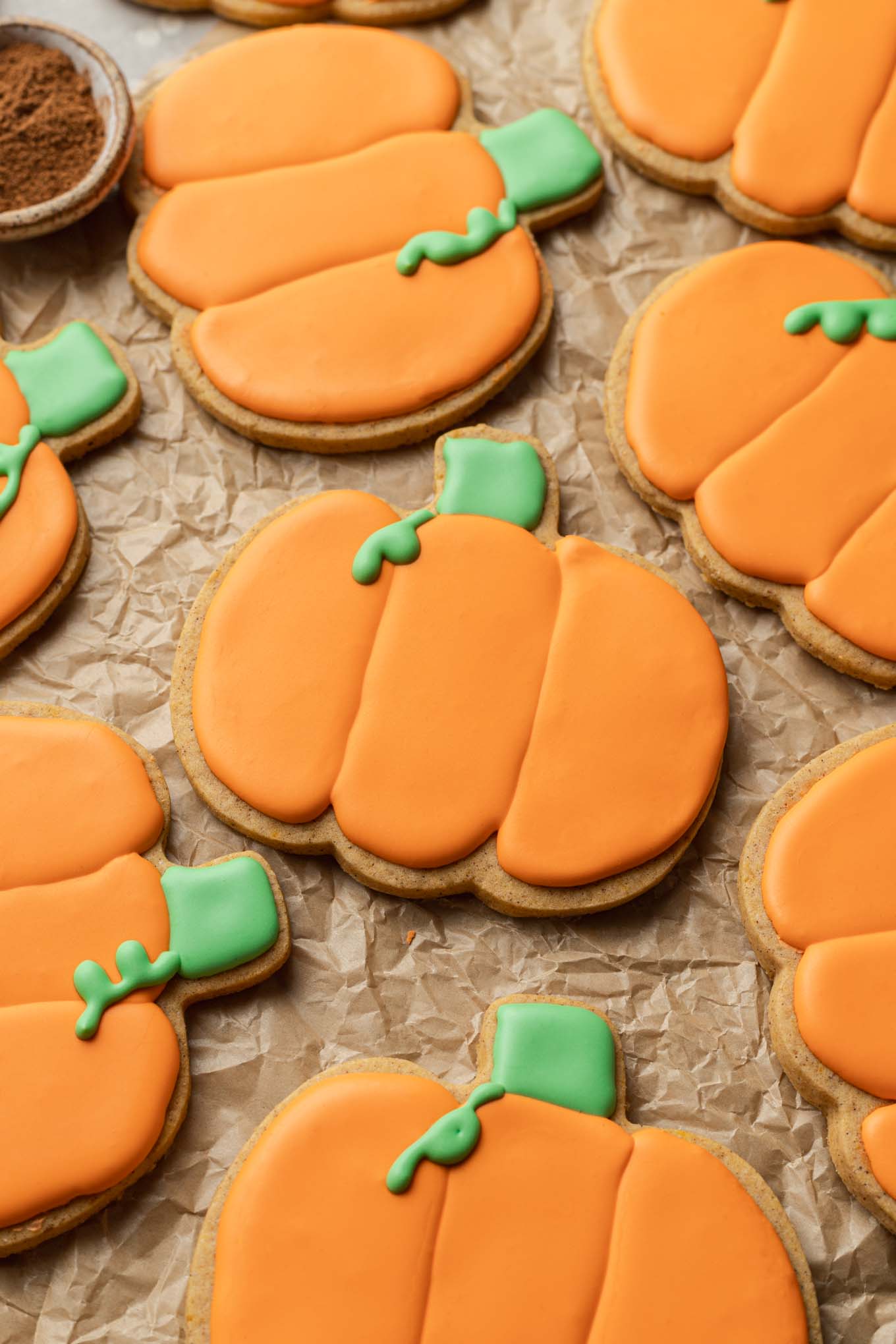 A close-up, overhead view of pumpkin sugar cookies on parchment paper. 