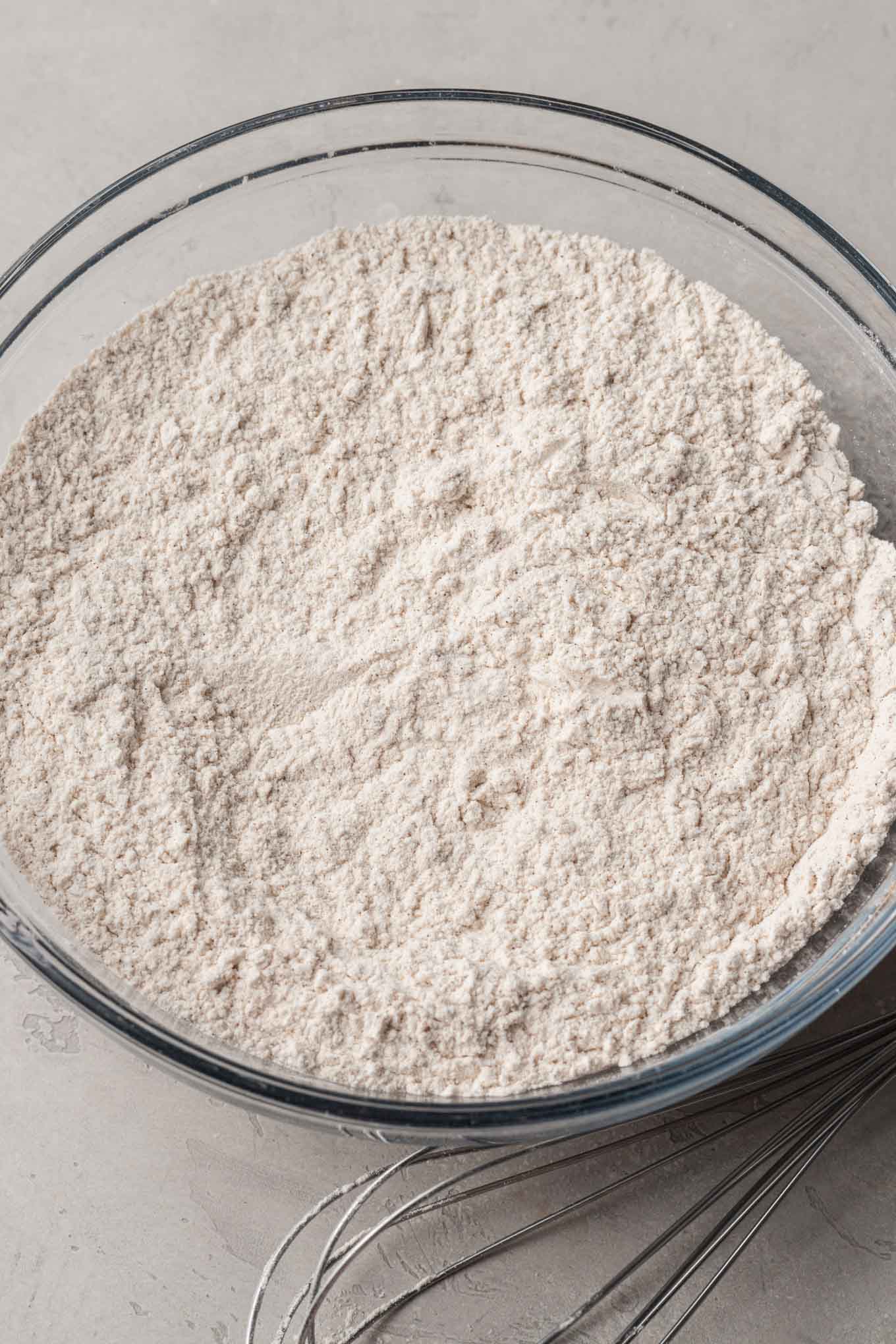 An overhead view of dry cookie ingredients in a glass mixing bowl. 