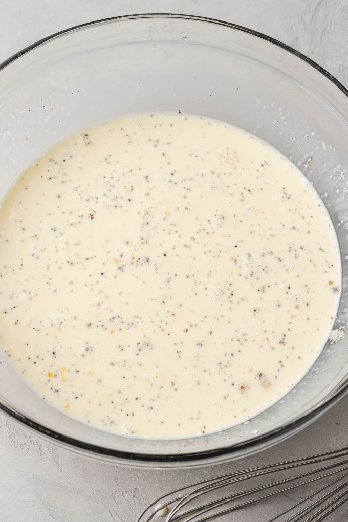 The egg mixture for a quiche whisked together in a glass mixing bowl.