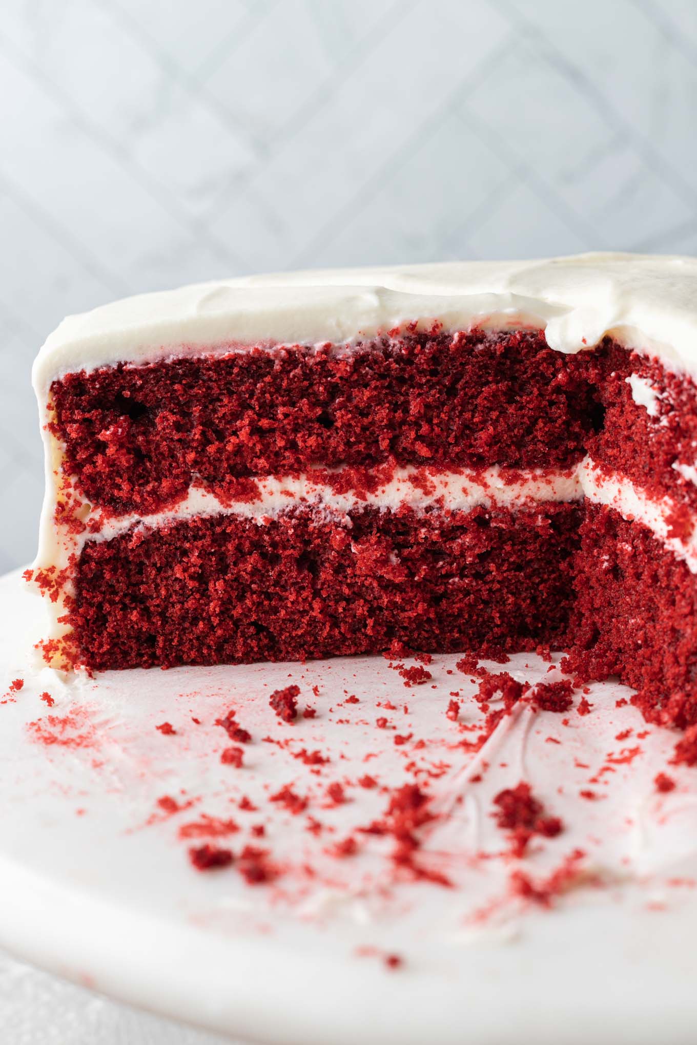 A side view of a sliced red velvet cake with cream cheese frosting. 