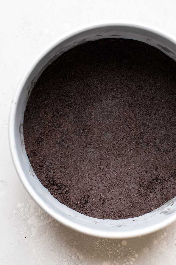 Overhead view of an Oreo crust packed into the bottom of a springform pan. 