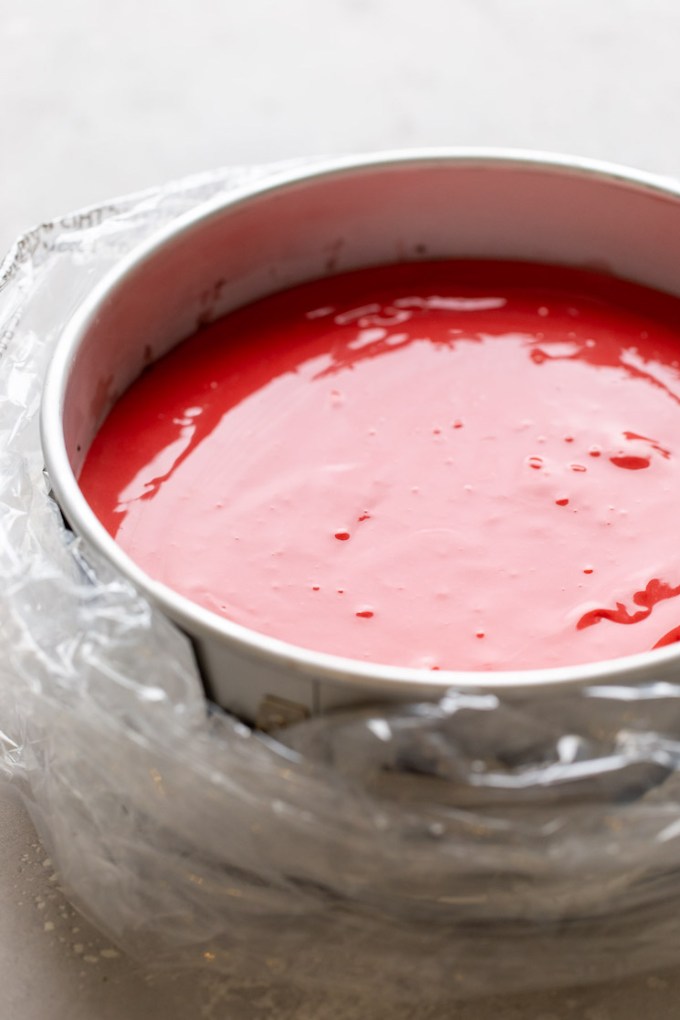 A springform pan wrapped in an oven bag and filled with red velvet cheesecake batter.