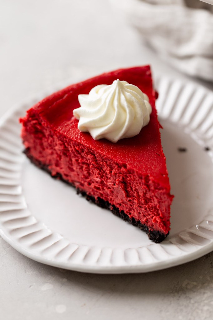 A slice of red velvet Oreo cheesecake on a white dessert plate. 