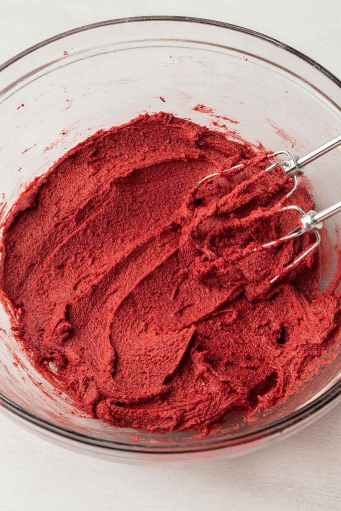 An overhead view of red velvet cookie dough in a glass mixing bowl.