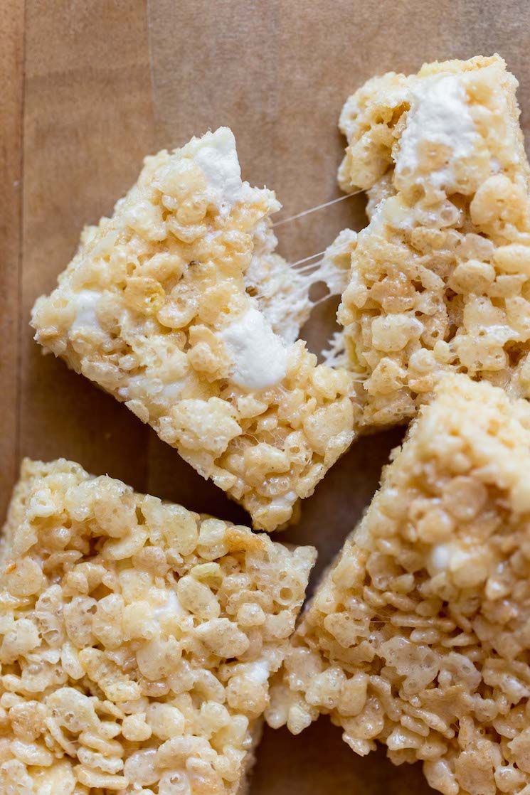 A close up image of a Rice Krispie treat being pulled apart with gooey marshmallow strings between the two halves.