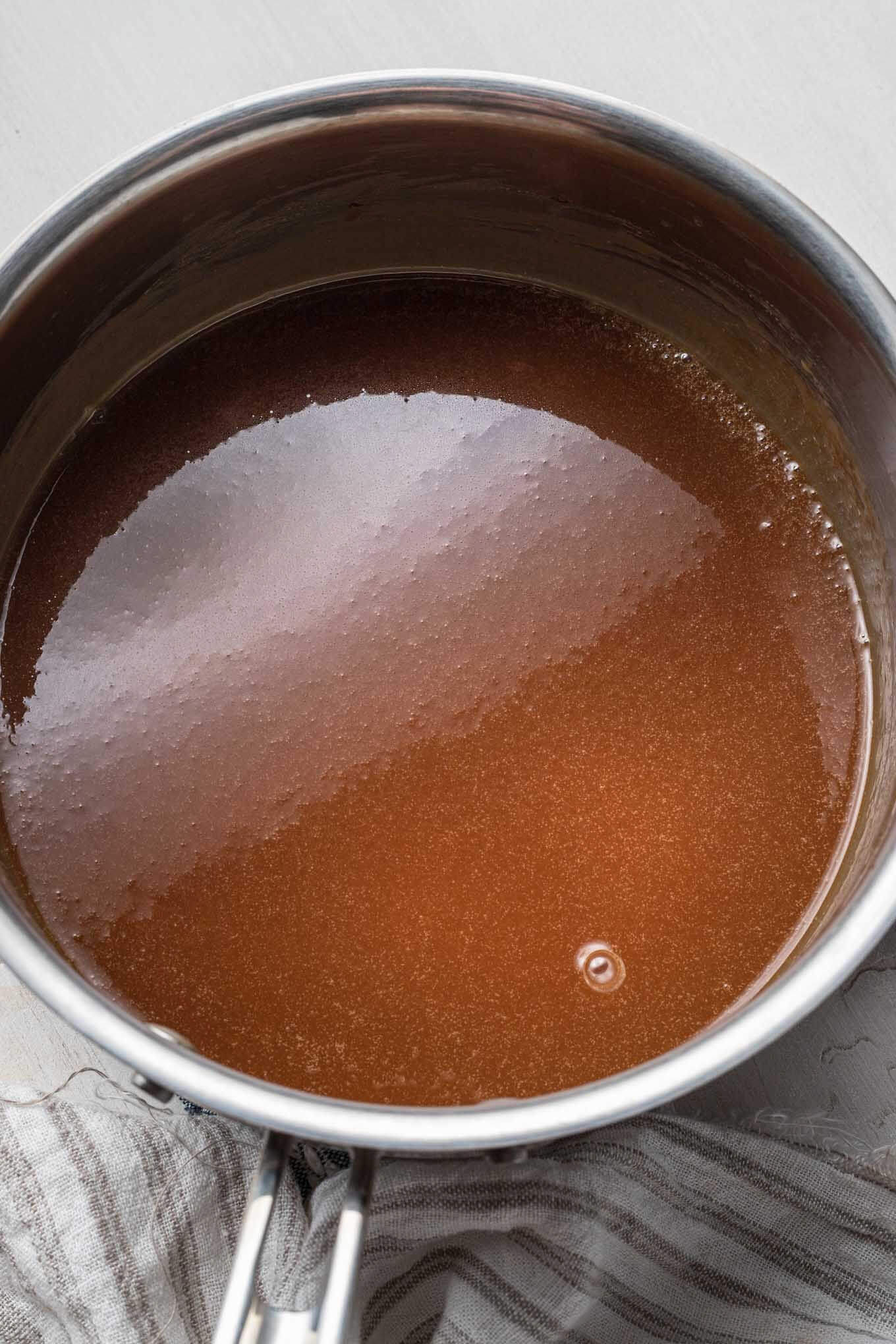Amber colored sugar mixture in a saucepan, ready for making caramel sauce.