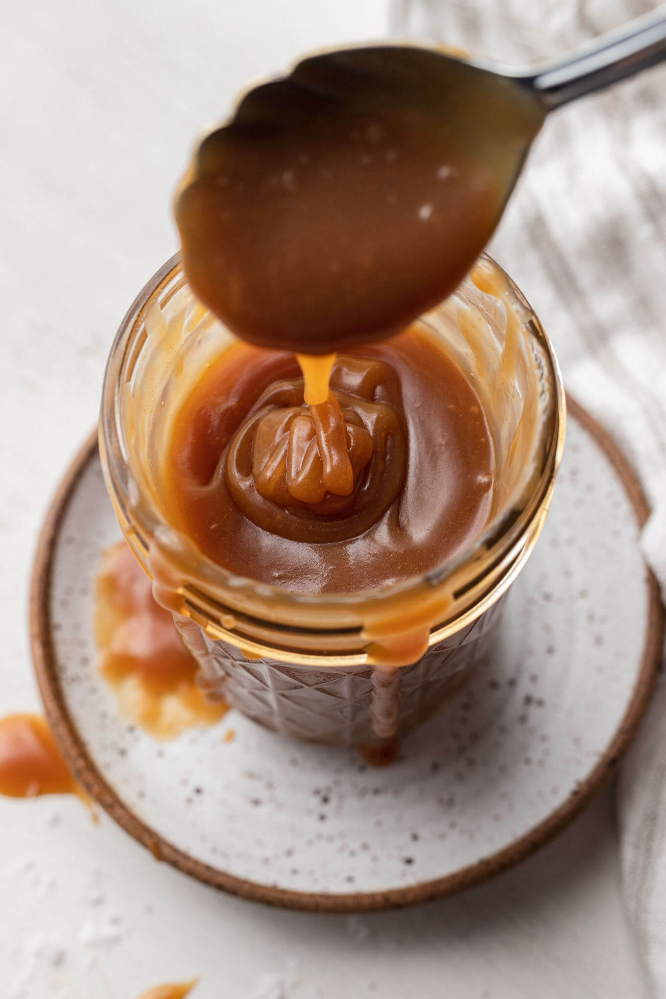 Salted caramel sauce being spooned into a mason jar. 