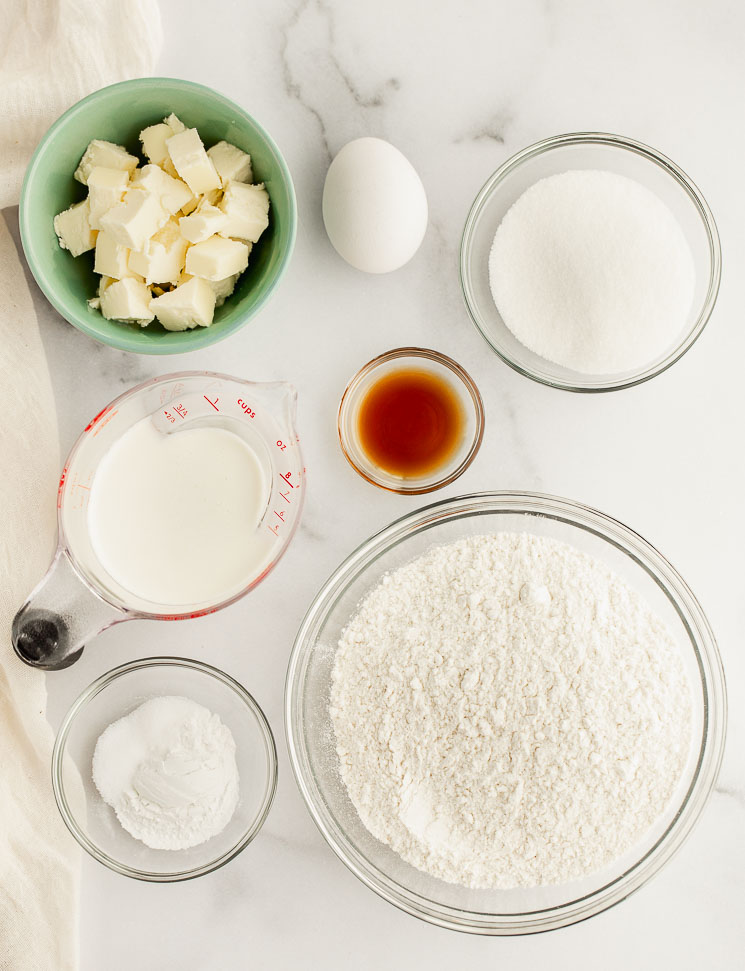 All of the ingredients needed to make scones measured out into glass bowls on a marble surface.