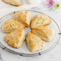 A batch of baked scones on a round wire rack.