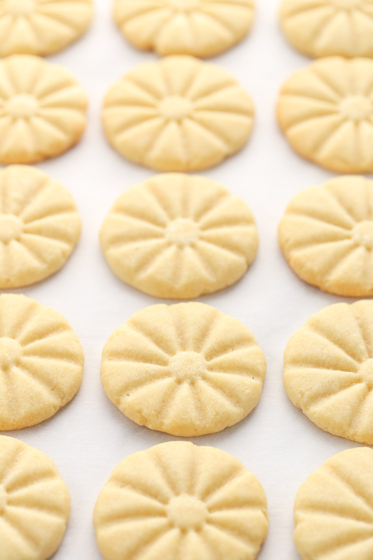 A baking sheet covered in parchment paper topped with shortbread cookies right out of the oven.