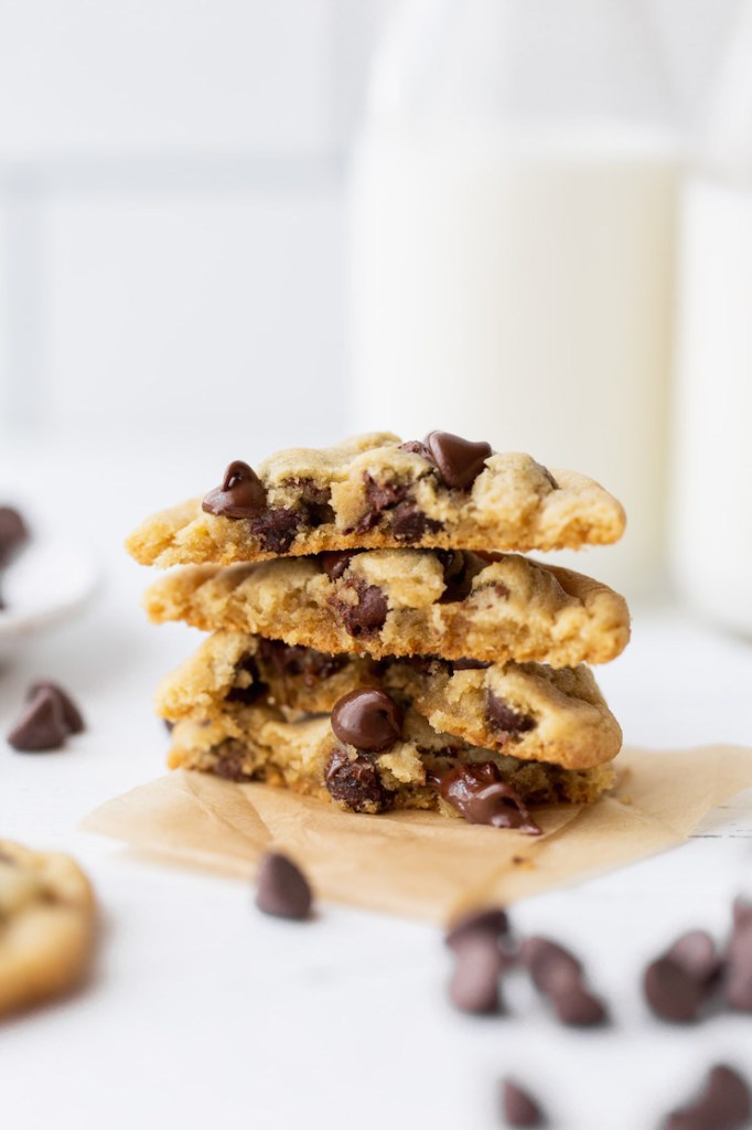 A stack of chocolate chip cookies cut in half showing the inside texture and melty chocolate chips.