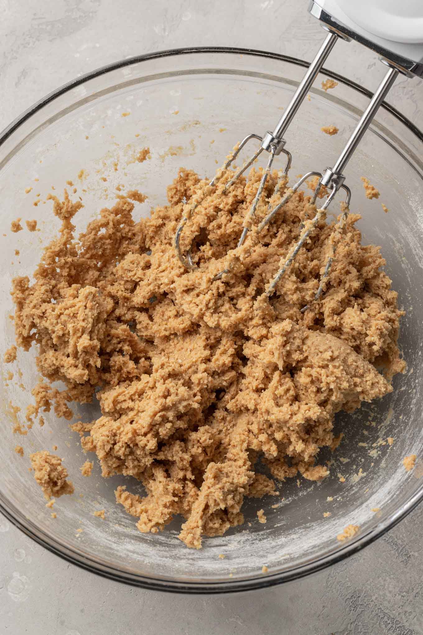 An overhead view of graham cracker cookie dough in a glass mixing bowl. 