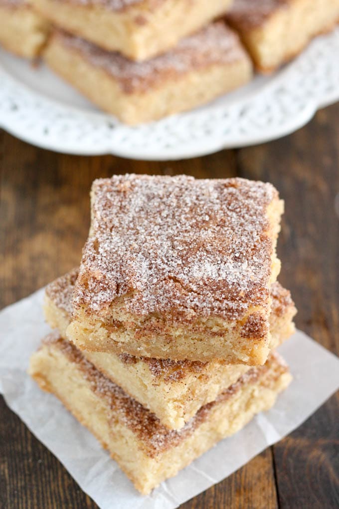 A stack of three snickerdoodle blondie bars on a square of parchment paper. 