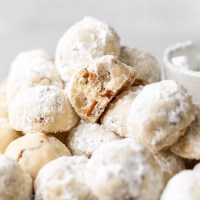 A batch of snowball cookies on a cooling rack.