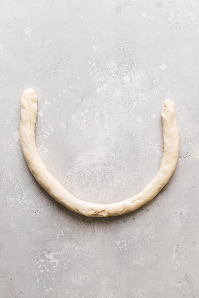 A roll of raw pretzel dough formed into a U shape.