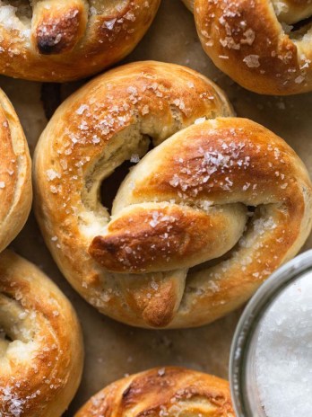 Overhead view of soft baked pretzels next to a dish of salt.