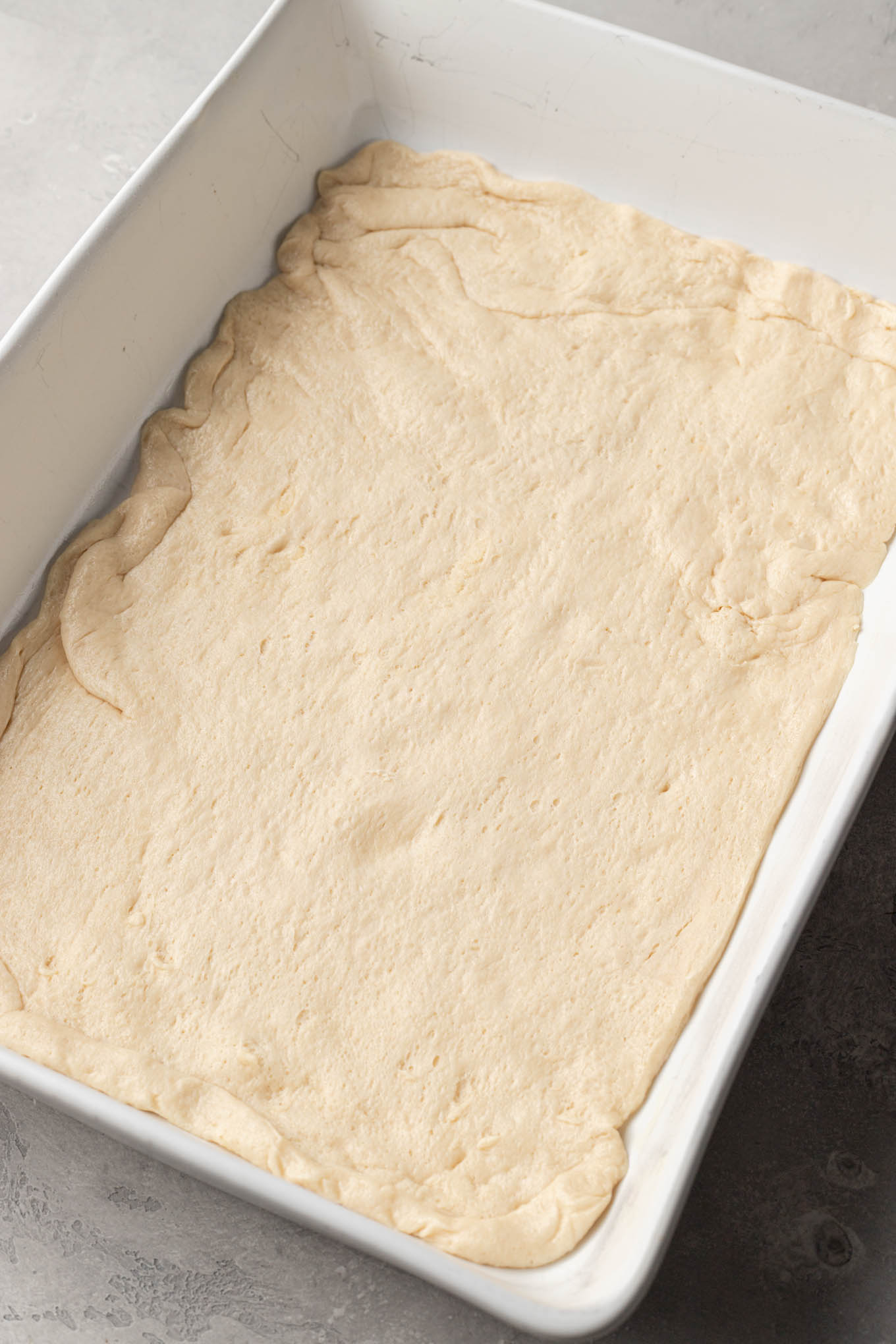 An overhead view of crescent roll dough stretched to cover the bottom of a 9x13-inch pan. 