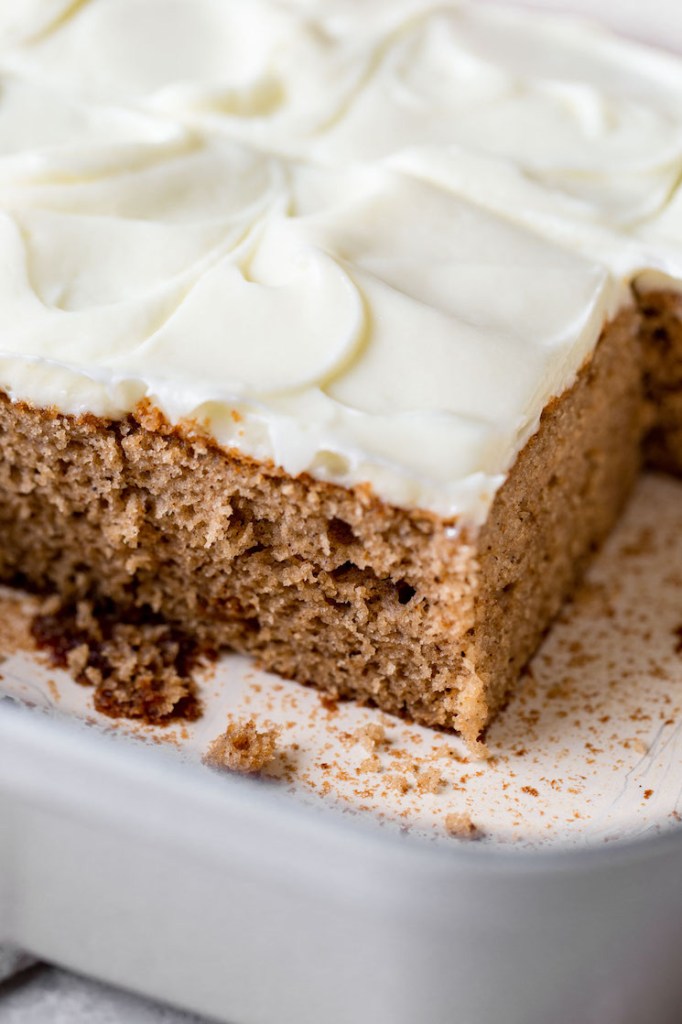 A side view of the spice cake in the baking pan with a few pieces removed to show the texture of the cake.