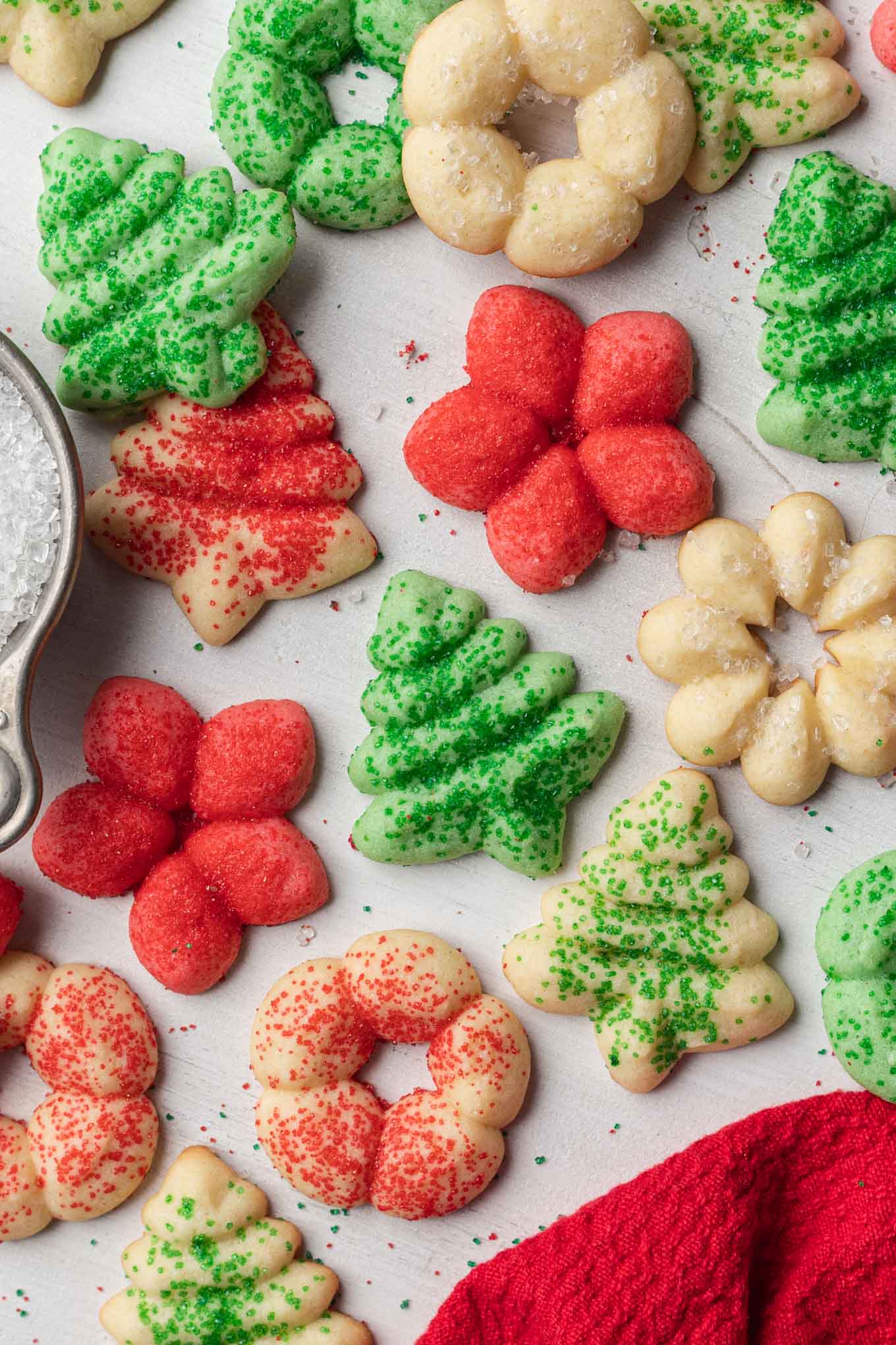 An overhead view of Christmas spritz cookies scattered over a white surface. 