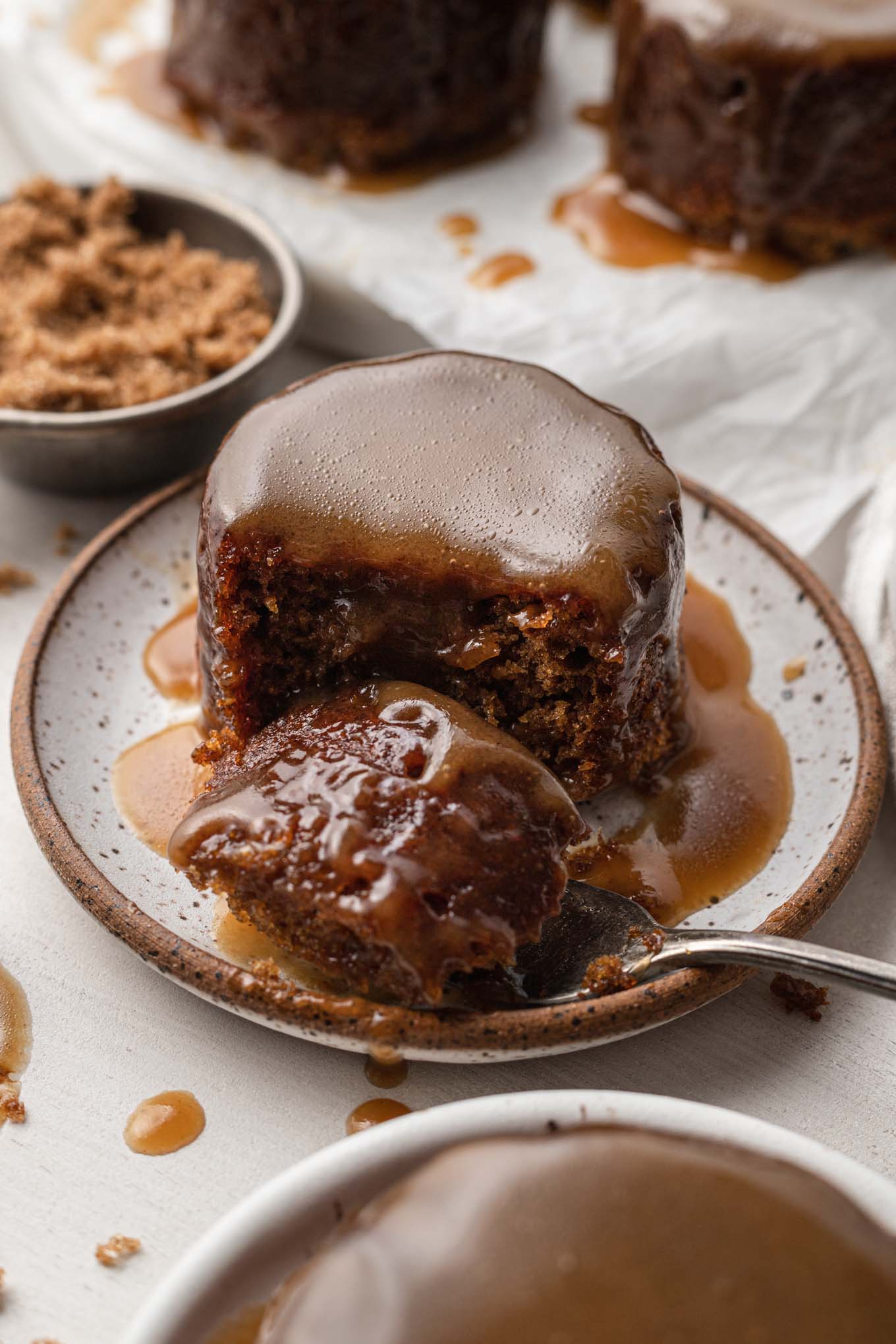 A forkful of sticky toffee pudding on a plate. 