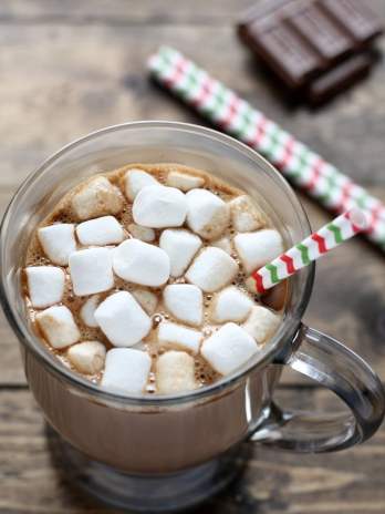 Mug of homemade hot chocolate topped with mini marshmallows and a straw.