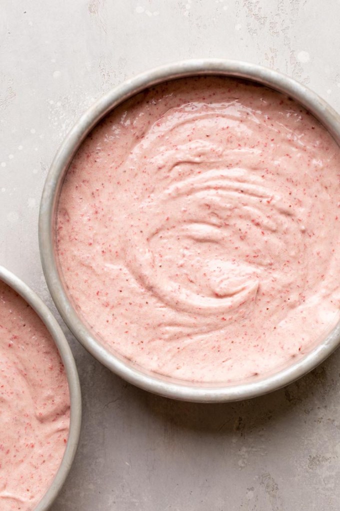 Strawberry cake batter poured into two round cake pans.