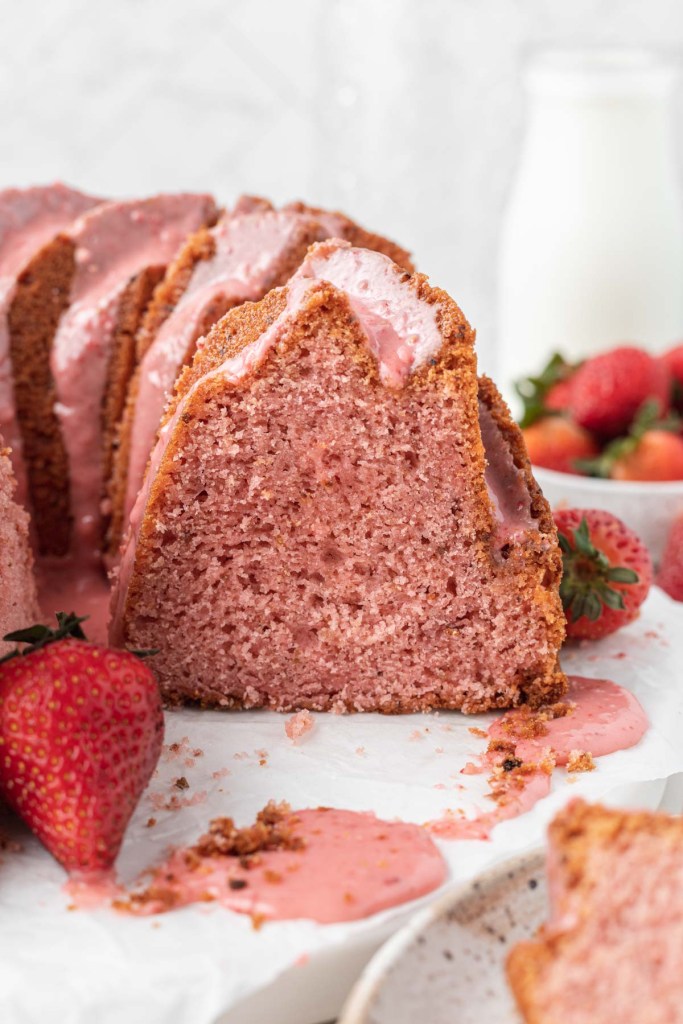 A side view of a sliced pound cake with strawberry glaze. 