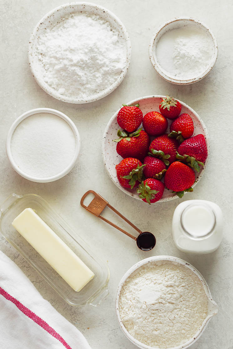 Several of the ingredients needed for strawberry shortcake on a gray surface.