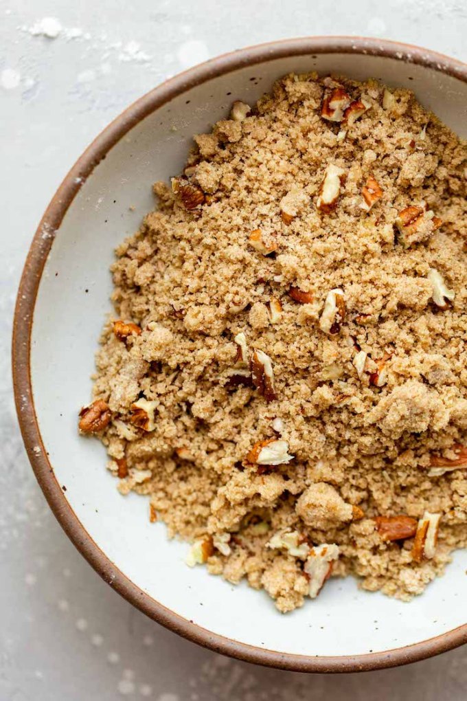 A white speckled plate holding pecan streusel topping.