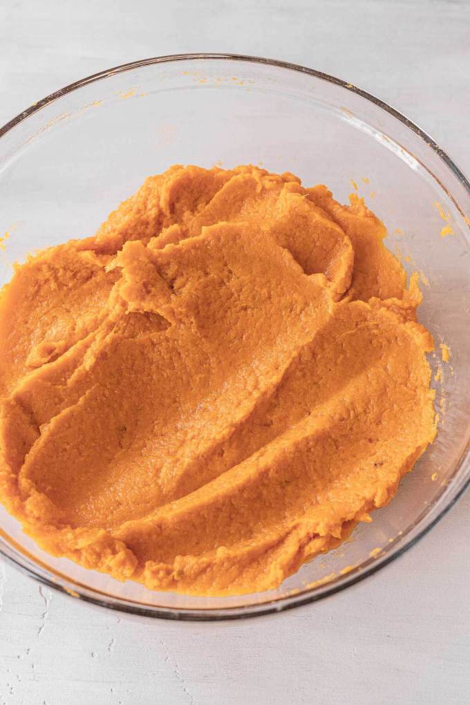 An overhead view of mashed sweet potatoes in a glass mixing bowl.