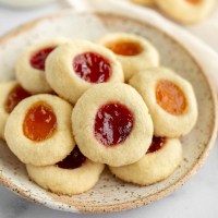 Thumbprint cookies sitting on top of a speckled plate.